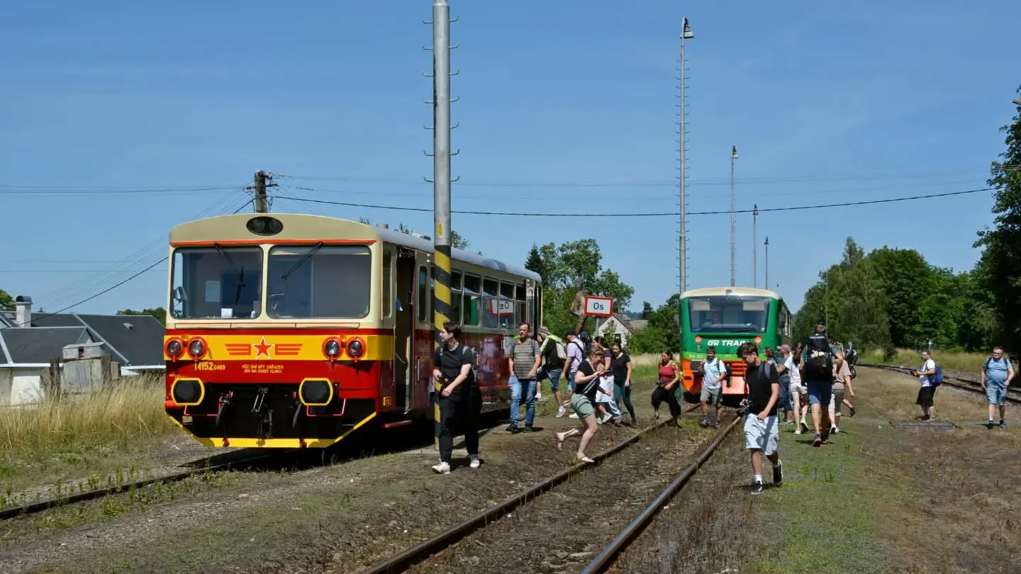 Historický motorový vůz a autobus stojí v Královci mezi cestujícími na obnovené trati.